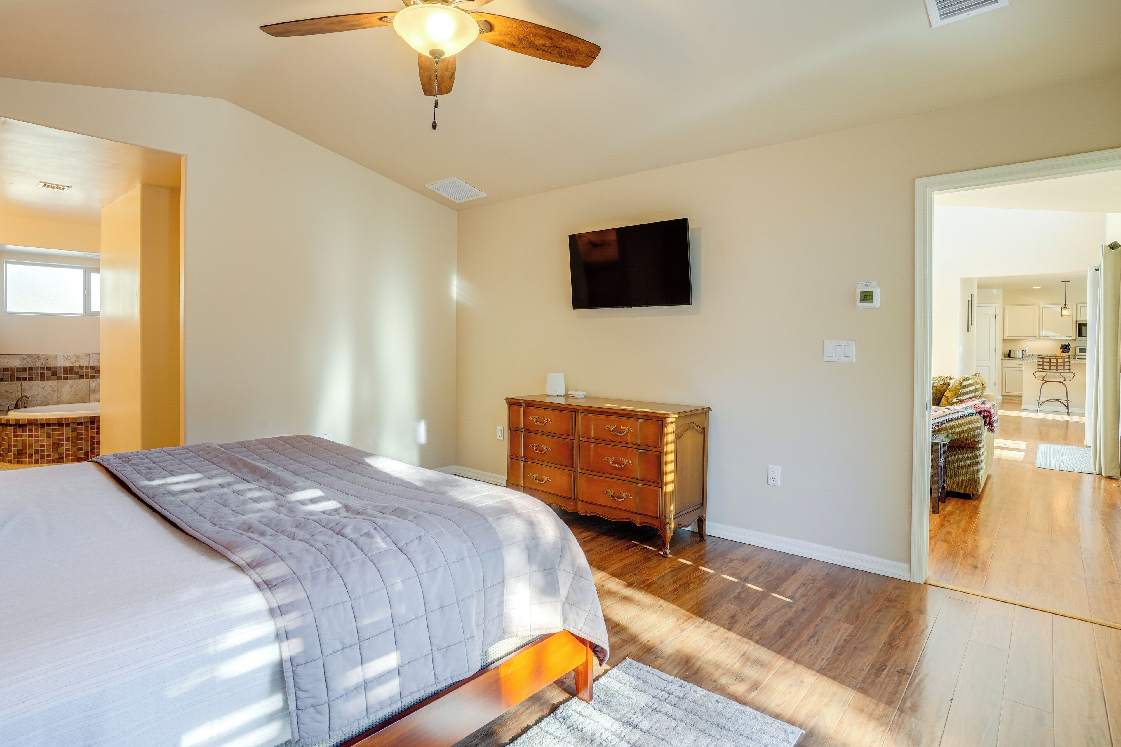 Une chambre à coucher avec un lit, une commode en bois et un téléviseur fixé au mur.