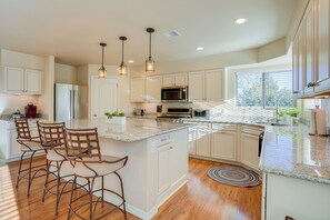 A modern kitchen with white cabinets, stainless steel appliances, and a central island with bar stools. - 3 Mi to Downtown Prescott - Spacious Home w/ Patio (Prescott)