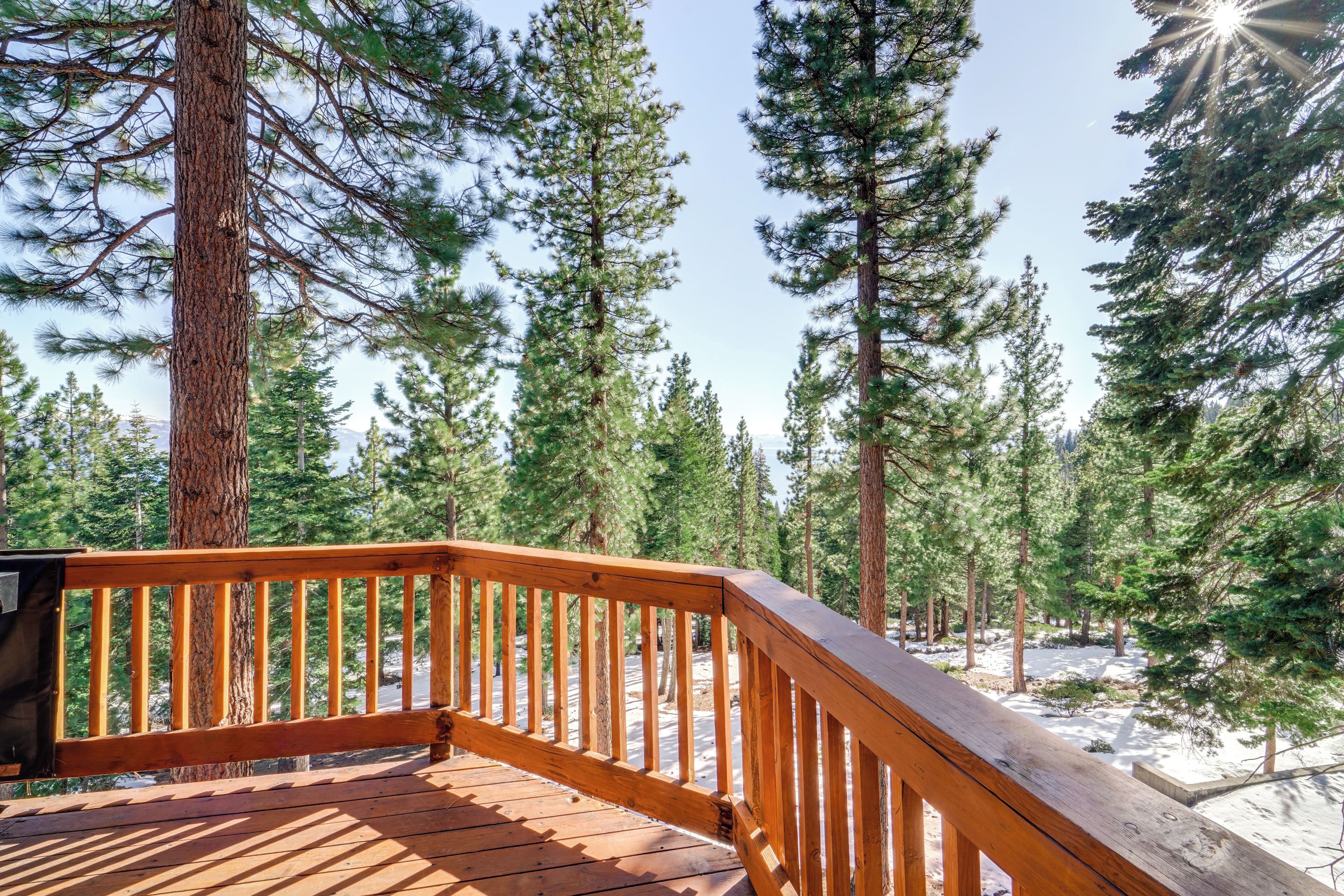 A wooden deck with a railing overlooking a forested area.