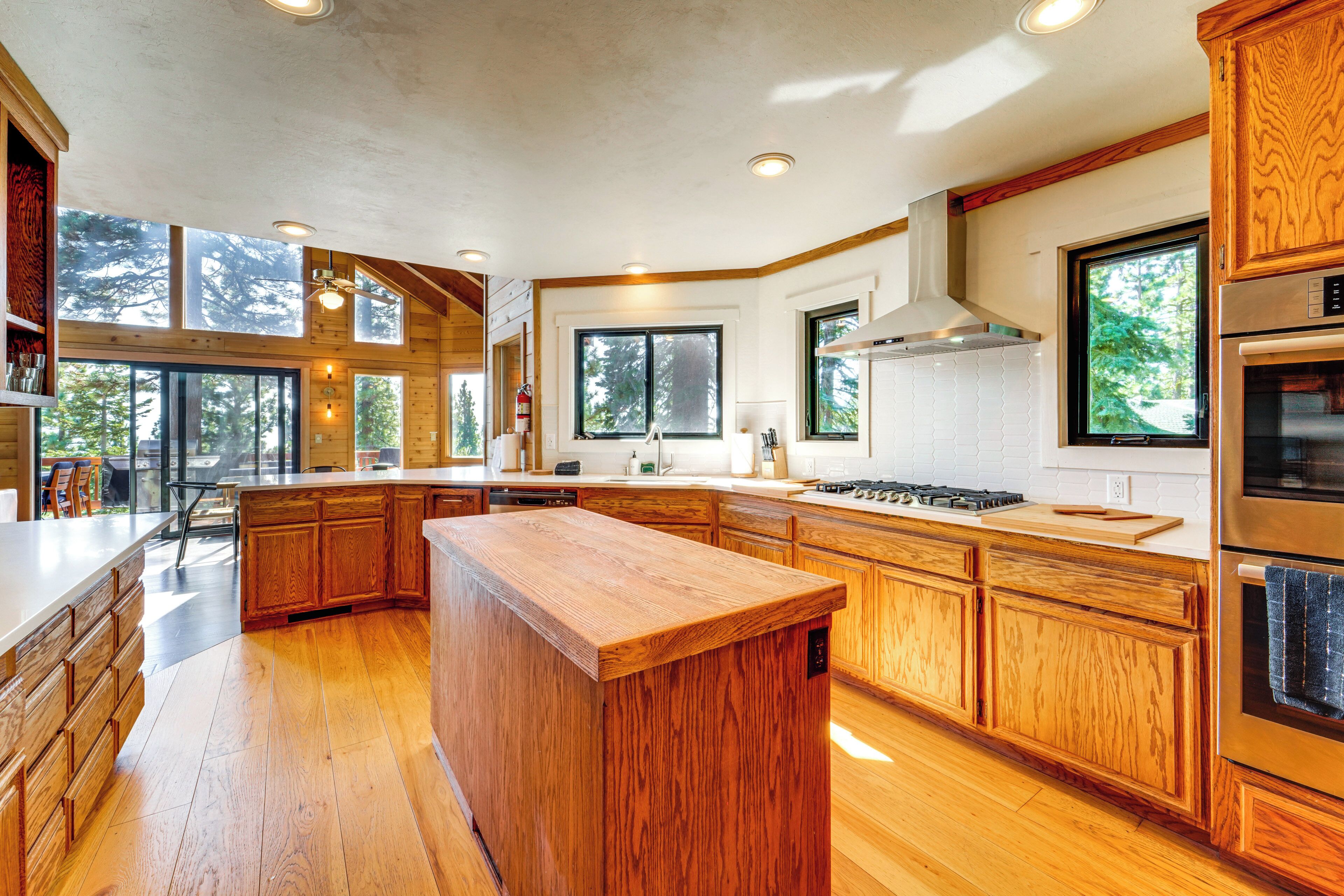 A spacious kitchen with wooden cabinets, a central island, and large windows providing natural light.
