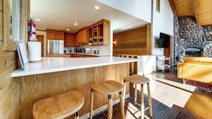 Una cocina moderna con armarios de madera, encimera blanca y chimenea de piedra.