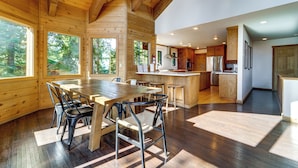 Un interior espacioso de madera con una gran mesa de comedor, sillas y una zona de cocina.