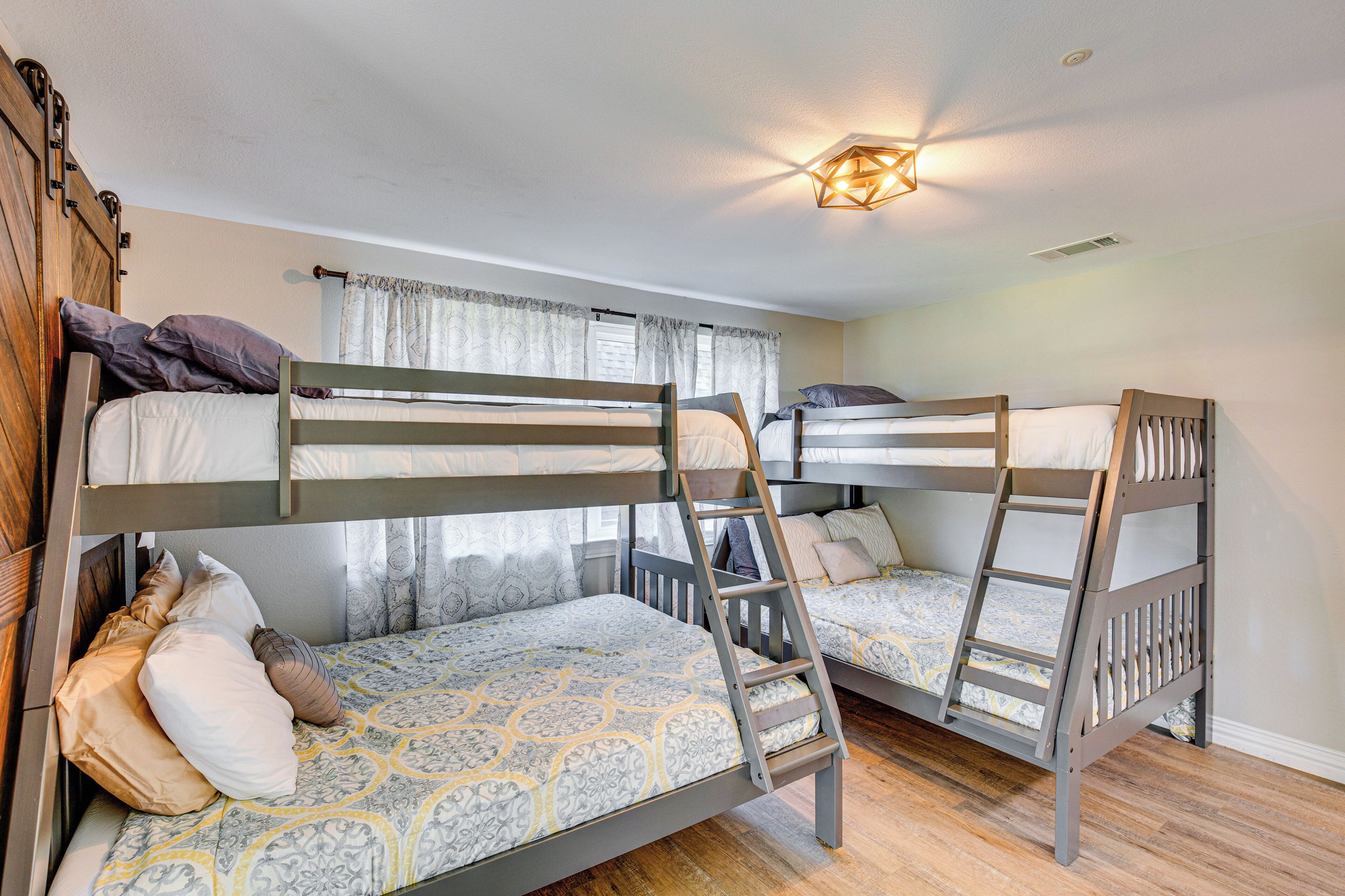 A room with three bunk beds, wooden headboards, and a ladder.