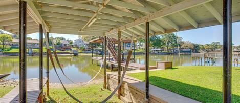 A covered outdoor area with a concrete floor, metal beams, and a hose.
