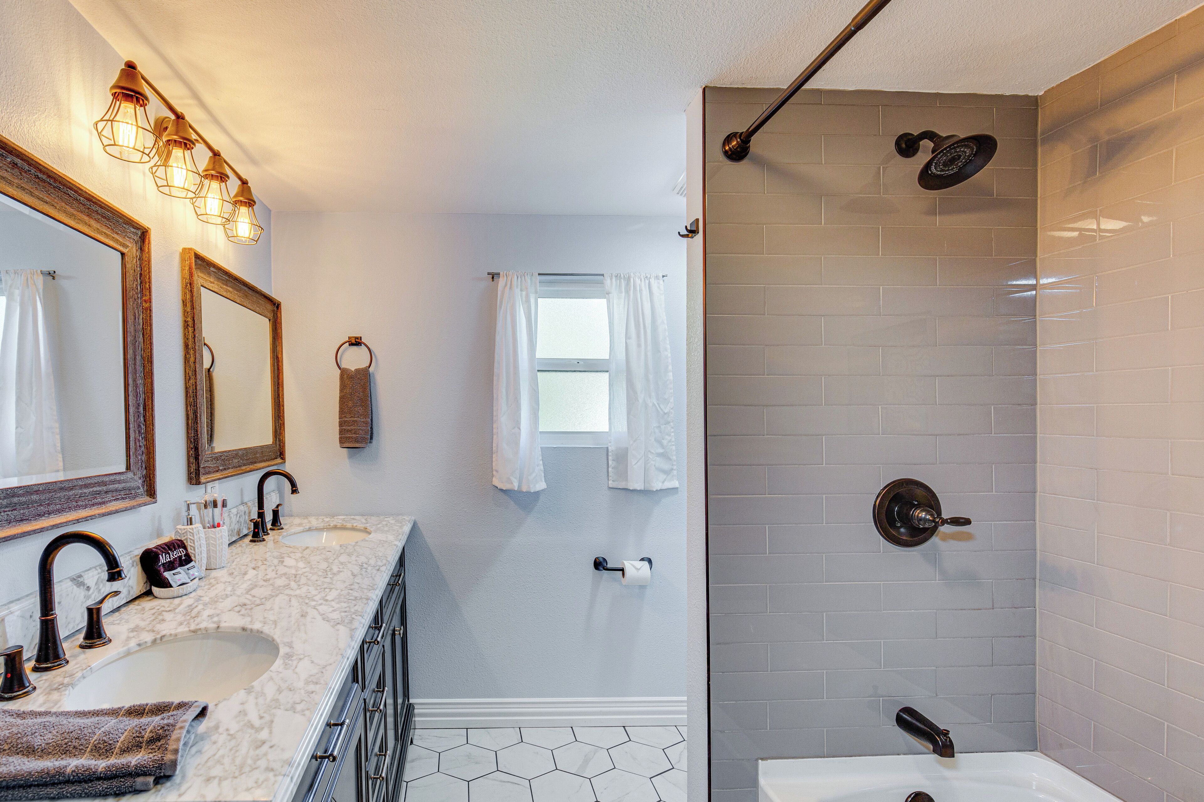 A bathroom with two sinks, a shower, and a vanity with a mirror.