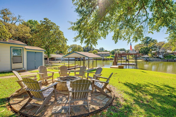 A patio with Adirondack chairs, a fire pit, and a pond.