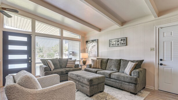 A living room with a sectional sofa, a chair, and a coffee table. There is a door, a window with blinds, and a lamp on a side table. - 5 Mi to Texas City Dike & Beach! Family Hideaway (Texas City)
