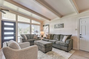 A living room with a sectional sofa, a chair, and a coffee table. There is a door, a window with blinds, and a lamp on a side table. - 5 Mi to Texas City Dike & Beach! Family Hideaway (Texas City)