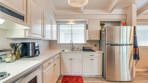 A modern kitchen with white cabinetry, a stainless steel refrigerator, and a red rug. - 5 Mi to Texas City Dike & Beach! Family Hideaway (Texas City)