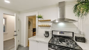 A modern kitchen with a stainless steel range hood, a built-in stove, and a coffee maker. - NYC Area Apartment on Hudson River! (Hastings-On-Hudson)
