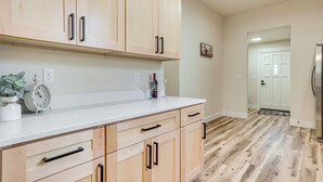 Une cuisine avec des meubles de rangement en bois, un plan de travail blanc et un plancher en bois.