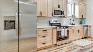 Une cuisine moderne dotée d’appareils électroménagers en acier inoxydable, de meubles en bois et d’un four encastré.