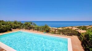 A swimming pool with a wooden deck and a view of the sea. - Residence with pool in Costa Paradiso (Trinità d'Agultu e Vignola)