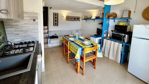A compact kitchen with a dining table, a sofa, and a refrigerator. - Residence with pool in Costa Paradiso (Trinità d'Agultu e Vignola)