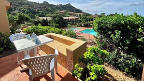 A terrace with a table and chairs, overlooking a swimming pool and lush greenery. - Residence with pool in Costa Paradiso (Trinità d'Agultu e Vignola)