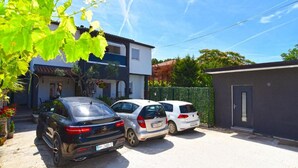 A residential area with two parked cars, a house with a balcony, and a small building. - Welcoming Apartment With Shared Pool (Fazana)