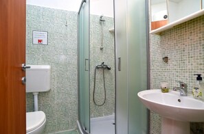Une salle de bain comprenant des toilettes, une douche avec une porte en verre et un lavabo avec un miroir au-dessus.
