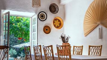 Un coin repas avec une table, des chaises et un ventilateur fixé au mur.