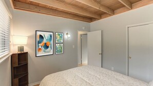 A bedroom with a bed, a nightstand, a wall-mounted lamp, and artwork. - 3956 La Casa de Estrella Marie - Backyard Games! (Del Rey Oaks)