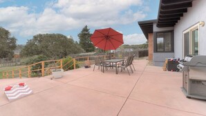 An outdoor patio with a table and chairs, a red umbrella, and a barbecue grill. - 3956 La Casa de Estrella Marie - Backyard Games! (Del Rey Oaks)
