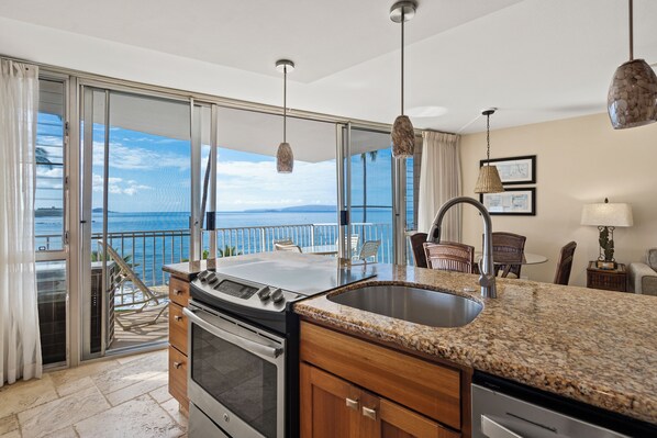A kitchen with a large island, a stove, and a sink.