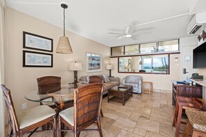 A spacious living area with a glass dining table, wicker chairs, a sofa, and a ceiling fan. - Your Perfect Ocean View Retreat in a Desirable Location! -Kamaole Nalu #405:  (Kihei, Maui)