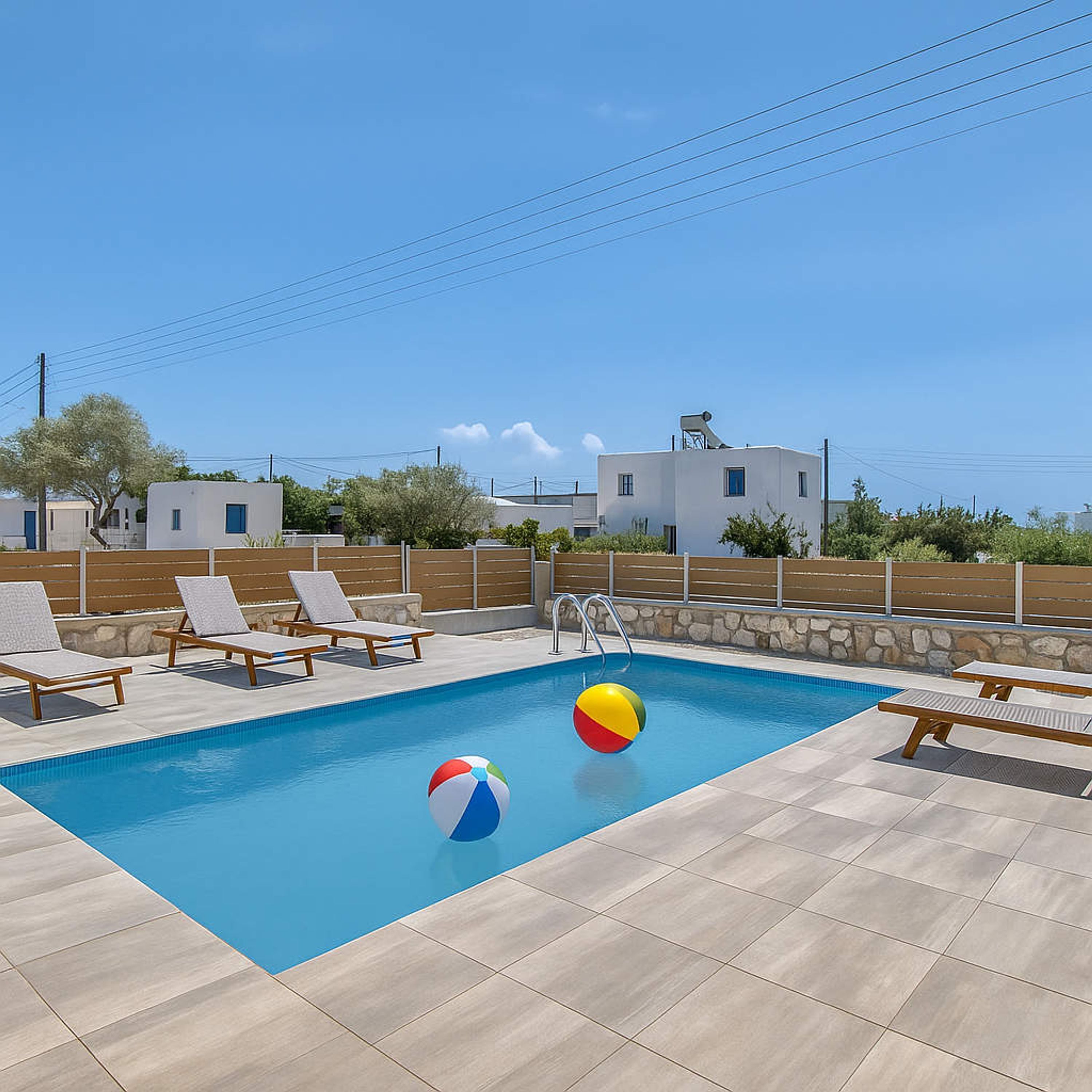 A swimming pool with lounge chairs and a beach ball.