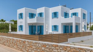 A modern white building with blue shutters, a stone wall, and a metal fence. - Venus s Seaside Bliss - Paros Dream Haven (Paros)