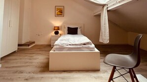 Une chambre à coucher avec un puits de lumière, un lit, une table de chevet avec une lampe, une chaise et une armoire.