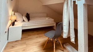 Une petite pièce agréable, dotée d’un plafond en pente et d’un puits de lumière, et comprenant un lit, un bureau et une chaise.