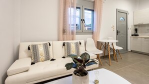 Een moderne woonkamer met een bank, een salontafel met een plant en een eethoek met stoelen en een tafel.