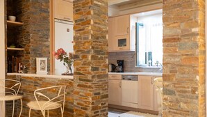 A kitchen with stone walls, a refrigerator, a coffee maker, and a window with a view.