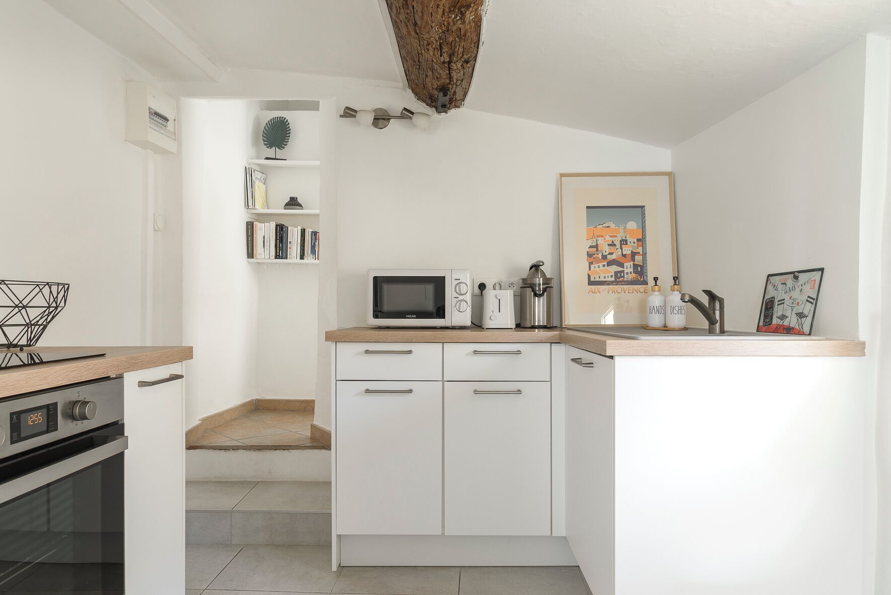 A modern kitchen with white cabinetry, a microwave, a toaster, and a coffee maker.