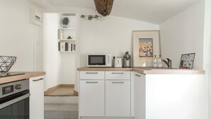 Une cuisine moderne avec des meubles blancs, un four à micro-ondes, un grille-pain et une machine à café.
