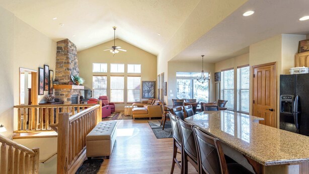 A spacious kitchen with a large island, wooden bar stools, and a stone fireplace. - Spacious Mountain Haven|Summer Fun at Granby Ranch (Granby)