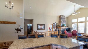 A spacious kitchen with a granite countertop, a stone fireplace, and a dining area with chairs. - Spacious Mountain Haven|Summer Fun at Granby Ranch (Granby)