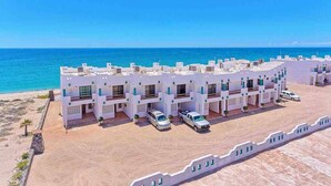 A coastal hotel with multiple white buildings, a sandy beach, and a clear blue sea. - Beachfront Paradise Villa #23 (Playa Encanto)