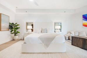 A modern bedroom with a large bed, bedside tables, a nightstand, a potted plant, and a painting. - Residence 303, Elegant Oasis on Seven Mile Beach (Seven Mile Beach)