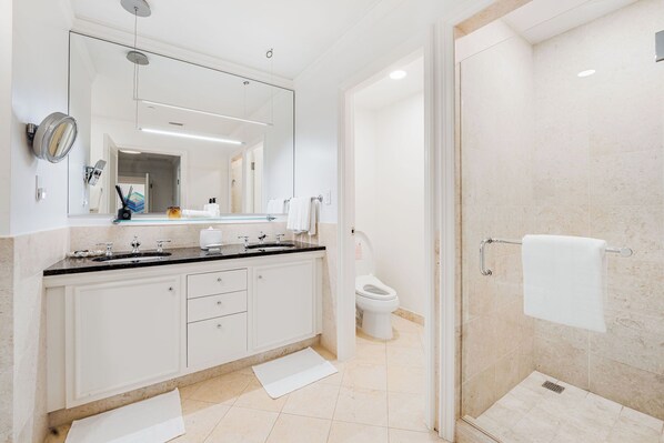 A modern bathroom with a large mirror, a shower area, and a toilet. - Residence 303, Elegant Oasis on Seven Mile Beach (Seven Mile Beach)