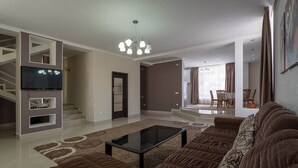 Uma sala de estar moderna com sofá seccional, mesa de centro de vidro e escada que leva a um andar superior.