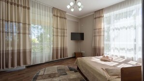Quarto com cama, televisão e cortinas.
