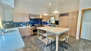 A modern kitchen with a central island, stainless steel appliances, and a blue backsplash. - OCEANBLOCK PROPERTY WITH AMAZING DECKS! (Rehoboth Beach)