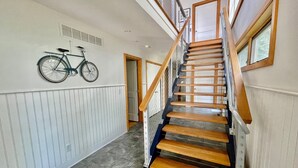 A staircase with wooden steps and a metal railing, leading to a door. A bicycle is mounted on the wall above the stairs. - OCEANBLOCK PROPERTY WITH AMAZING DECKS! (Rehoboth Beach)