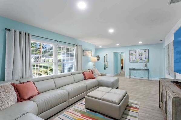 A modern living room with a sectional sofa, a coffee table, and a TV stand.