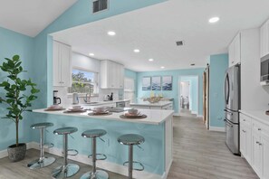 A modern kitchen with a central island, bar stools, and stainless steel appliances.