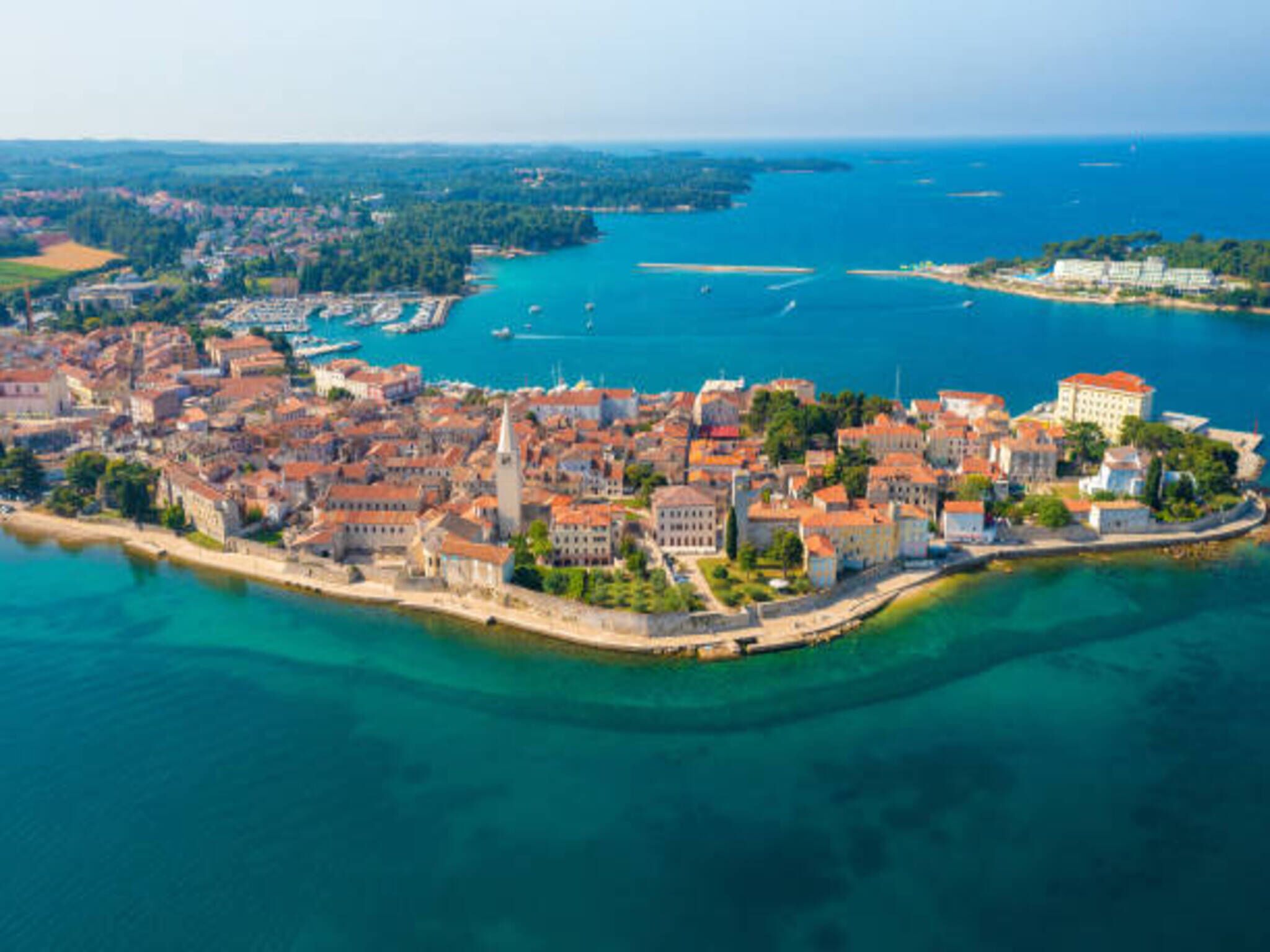 An aerial view of a coastal city with historic architecture, a marina, and clear blue waters.