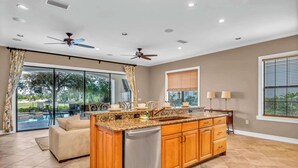 A modern kitchen with granite countertops, wooden cabinets, and stainless steel appliances. - Bright 5BR retreat w/ pool & fire pit (Kissimmee)