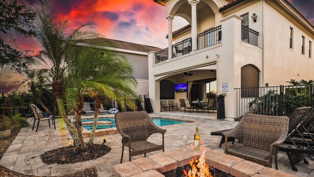 A poolside area with wicker furniture, a fire pit, and a pool. - Bright 5BR retreat w/ pool & fire pit (Kissimmee)