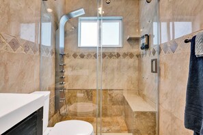 A modern bathroom with a glass-enclosed shower, a toilet, and a sink.