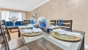 A dining table set with white napkins, blue glassware, and decorative vases. - Forget your worries in this spacious and serene space. (Miami)